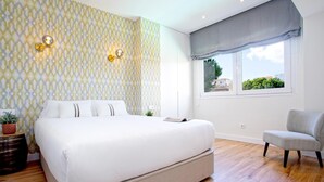 A bedroom with a large bed, a window with a view, and a chair. - Genteel Home Ricardo Soriano II (Marbella)