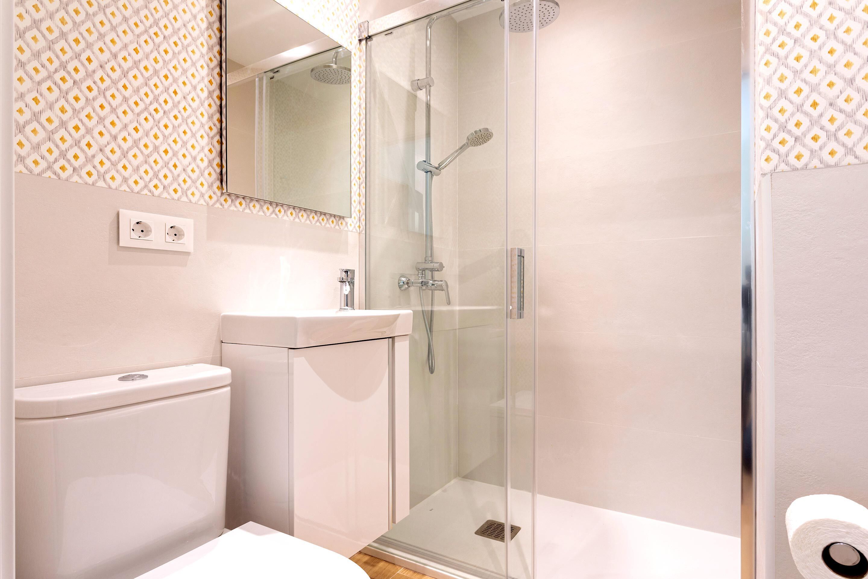 A modern bathroom with a glass-enclosed shower, a toilet, and a sink.
