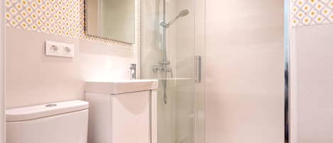 A modern bathroom with a glass-enclosed shower, a toilet, and a sink.