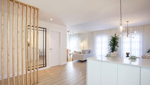 A modern kitchen with a white countertop, wooden flooring, and a hanging light fixture. - Genteel Home San Pancracio (Fuengirola)