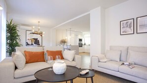 A modern living room with a sofa, coffee table, and a dining area. - Genteel Home San Pancracio (Fuengirola)