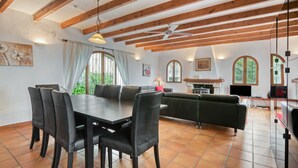A dining area with a table and chairs, a sofa, and a kitchen in the background. - Villa 'Casa Ann - Family Rentals' with Sea View, Private Pool and Wi-Fi (Jávea)
