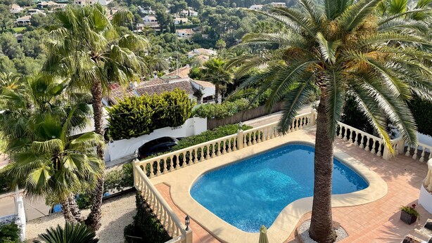A pool surrounded by palm trees and a view of a hillside town. - Villa 'Casa Ann - Family Rentals' with Sea View, Private Pool and Wi-Fi (Jávea)
