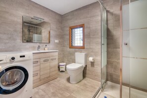 A modern bathroom with a washing machine, toilet, and glass shower enclosure. - Villa 'Casa Ann - Family Rentals' with Sea View, Private Pool and Wi-Fi (Jávea)