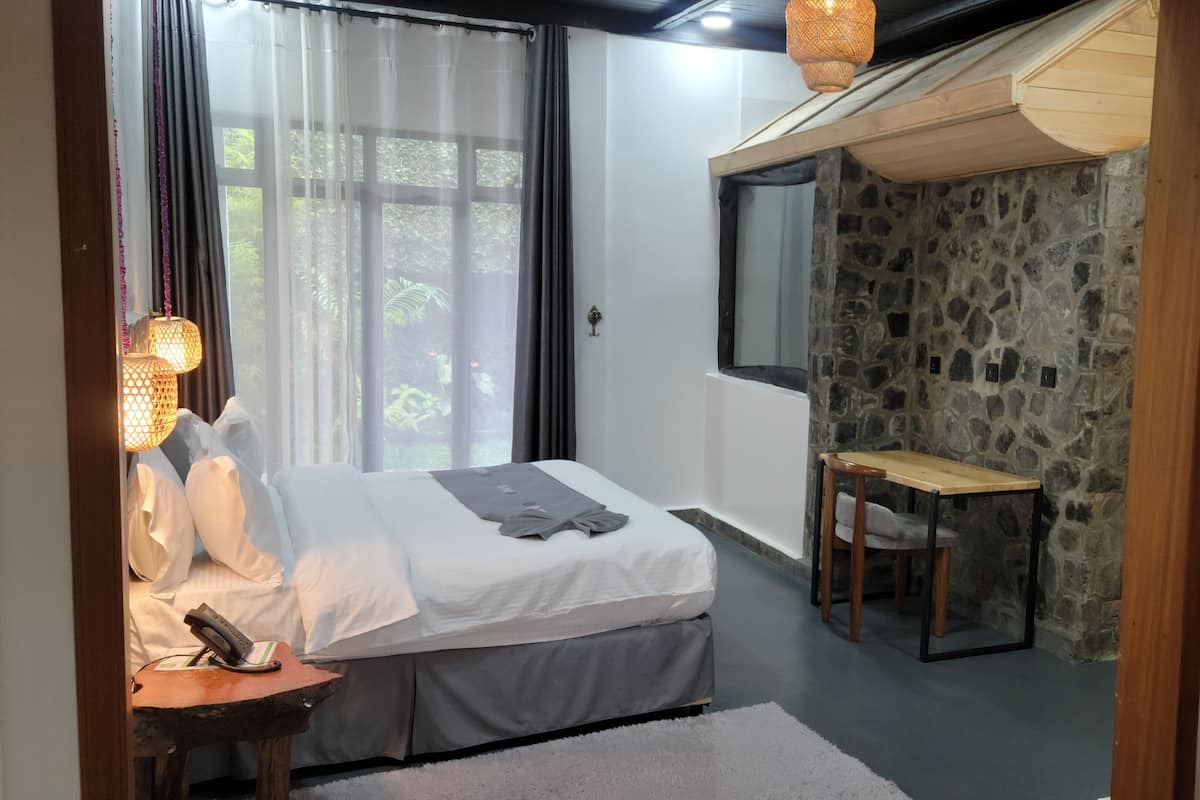 A bedroom with a bed, bedside table, and a desk.