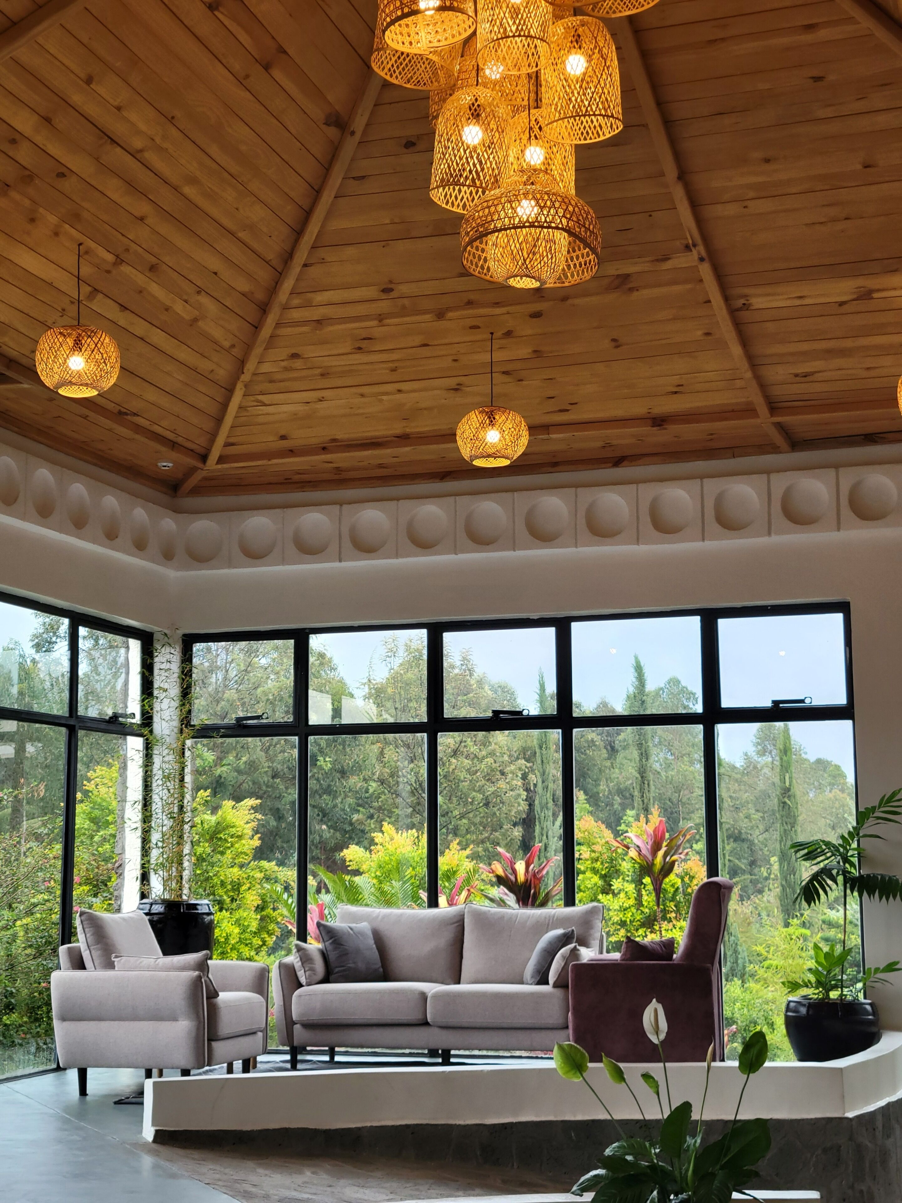 A spacious room with a high ceiling, large windows, and a modern sofa set.