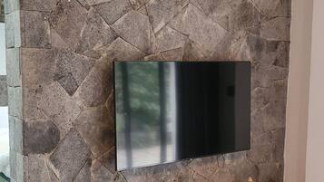 A flat-screen TV mounted on a stone wall with a wooden TV stand below.