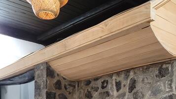 Una pequeña mesa de madera con una silla acolchada en un rincón, junto a una pared de piedra y una ventana.
