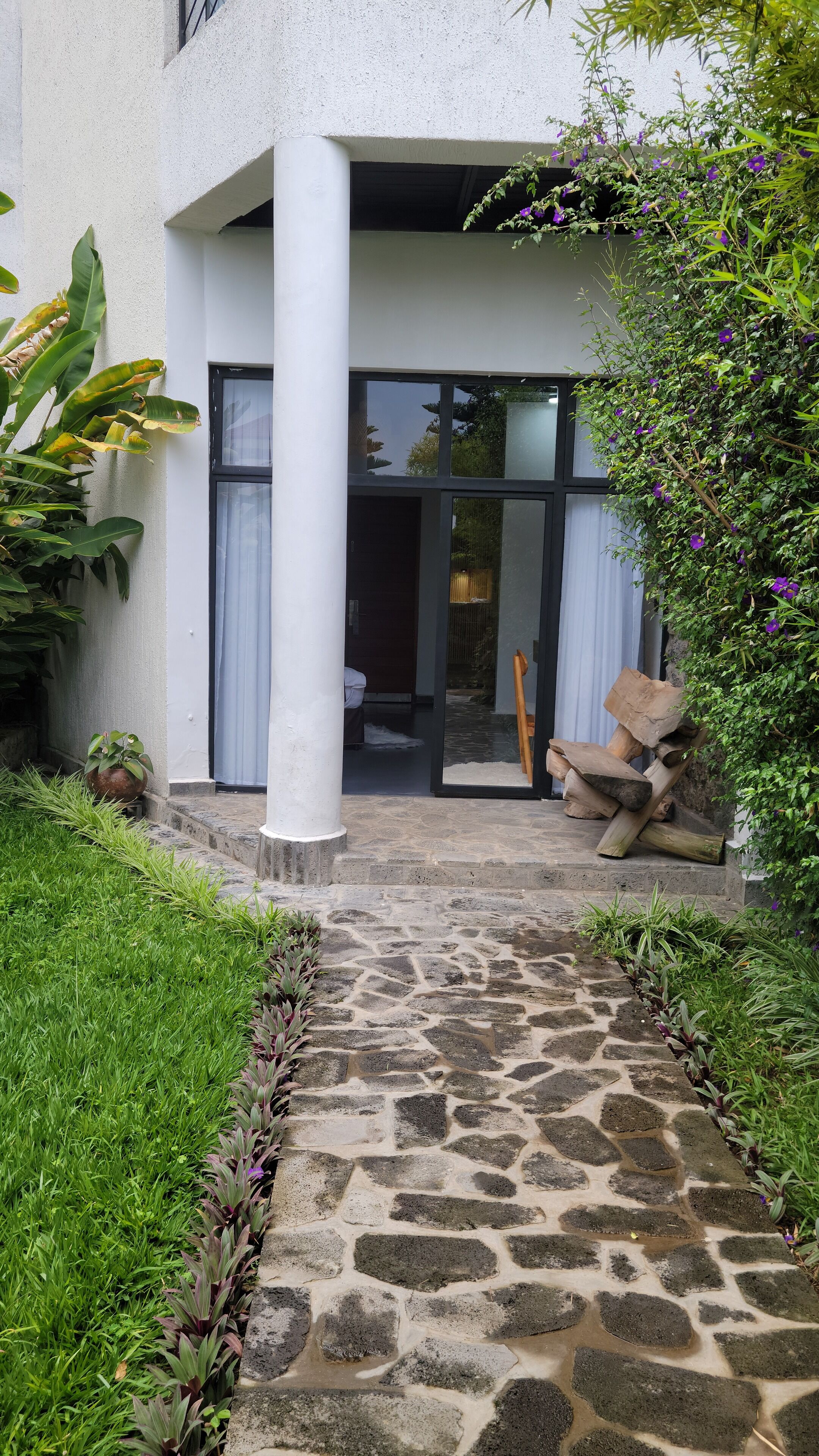 A stone pathway leading to a building with a white exterior and large glass doors.