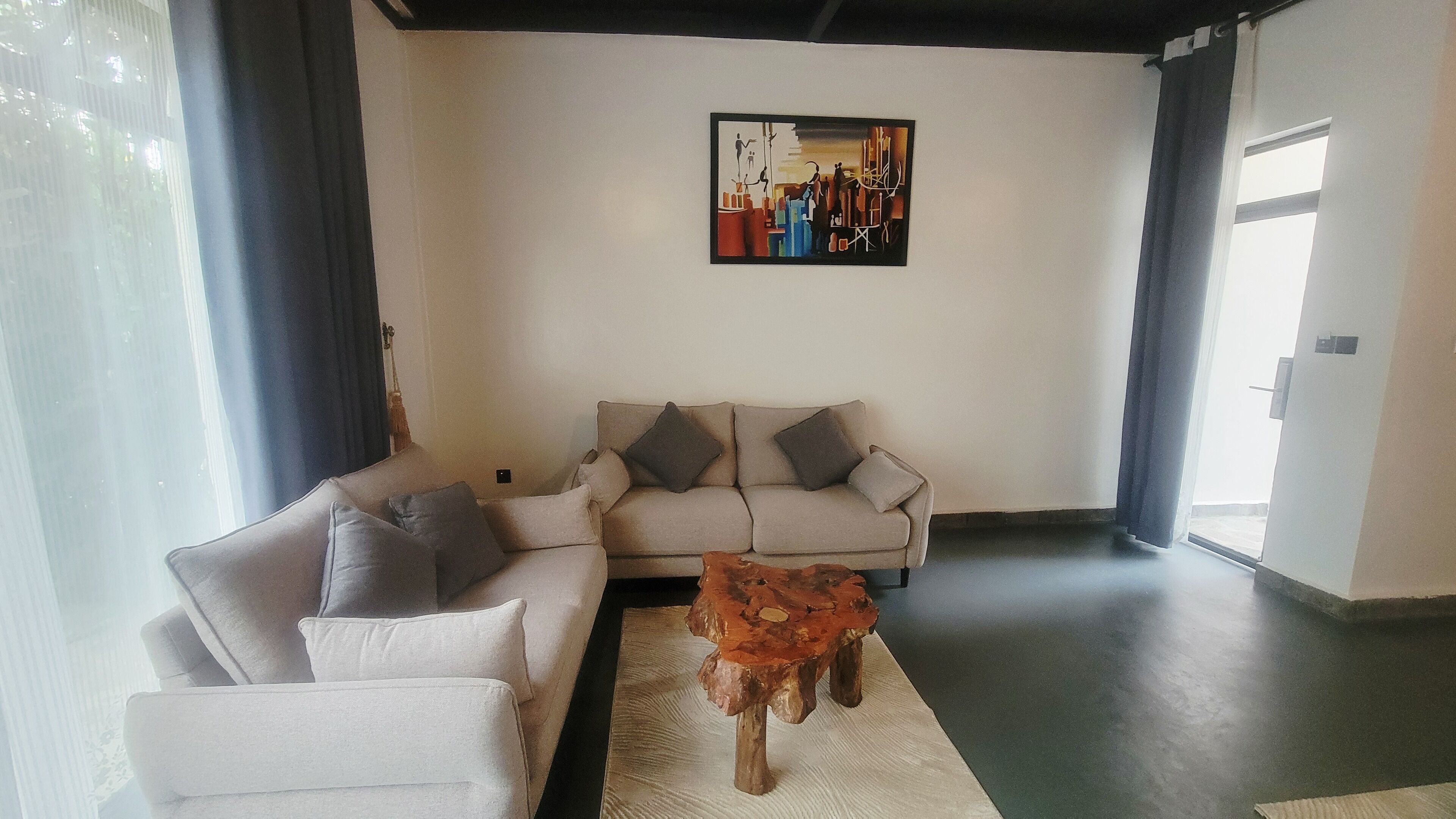 A living room with a sofa, a coffee table, and a painting on the wall.