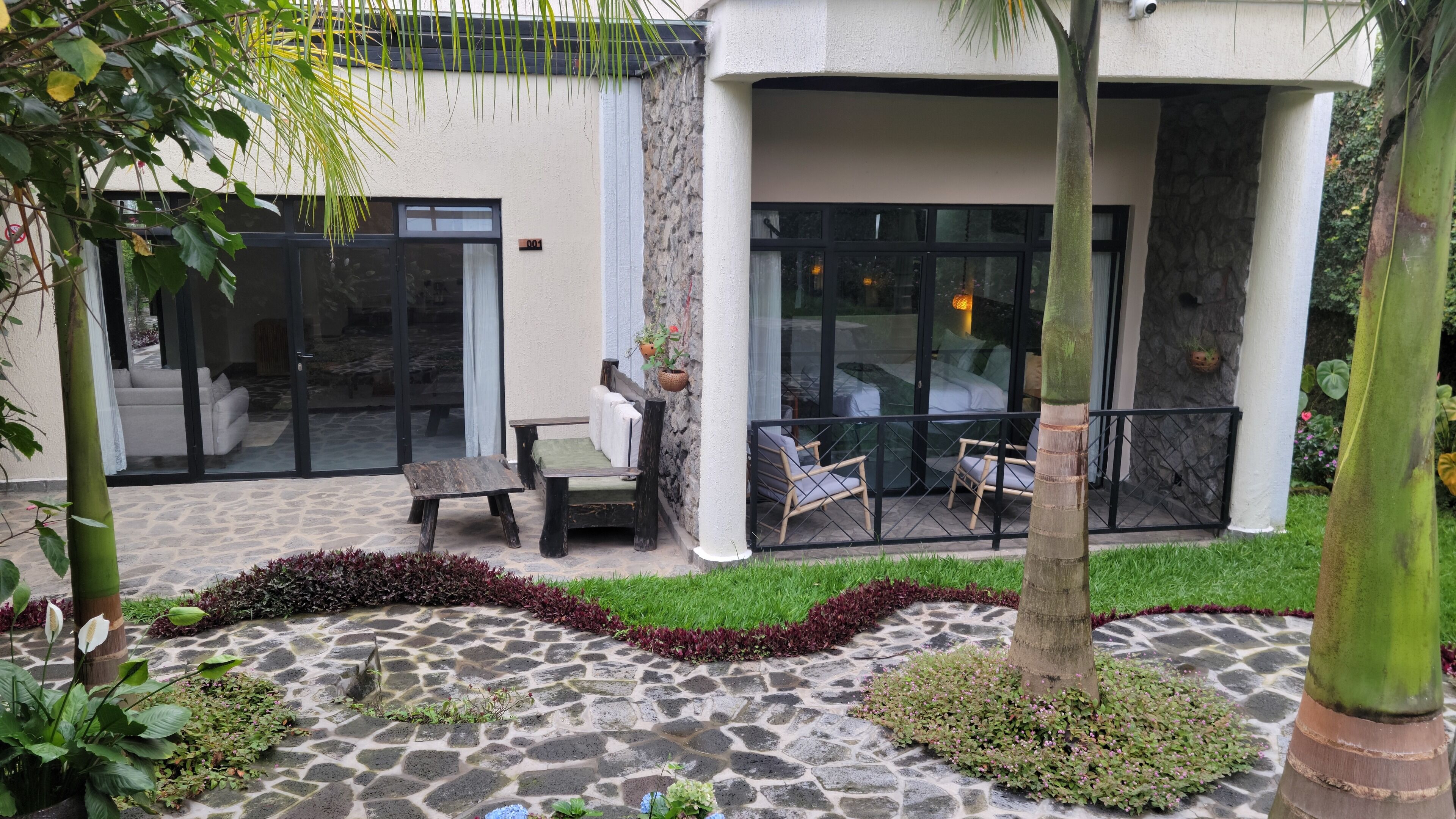 Eine moderne Außenpatio mit Steinböden, einer Sitzecke mit Tisch und Stühlen und Blick ins Innere durch große Glasüren.