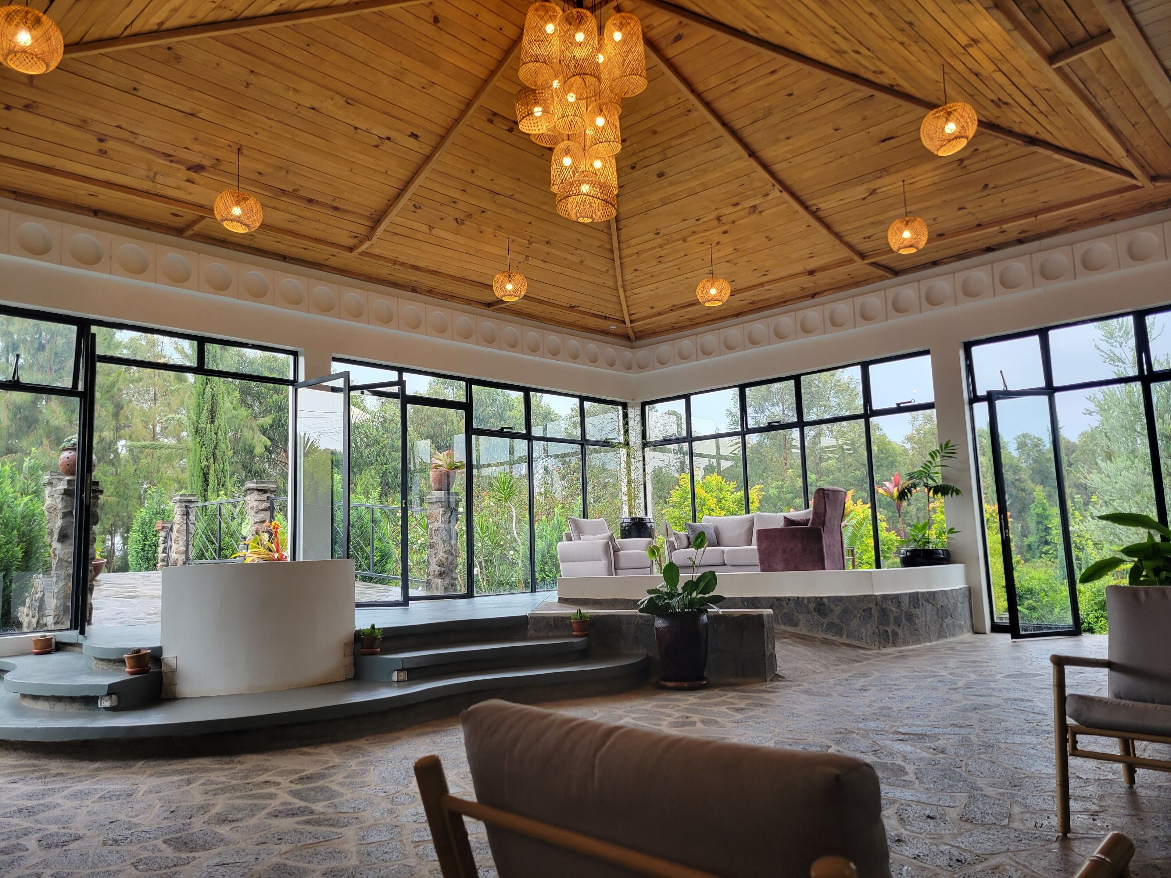 A spacious room with a high ceiling, large windows, and a stone floor.