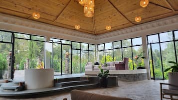 A spacious room with a high ceiling, large windows, and a stone floor.