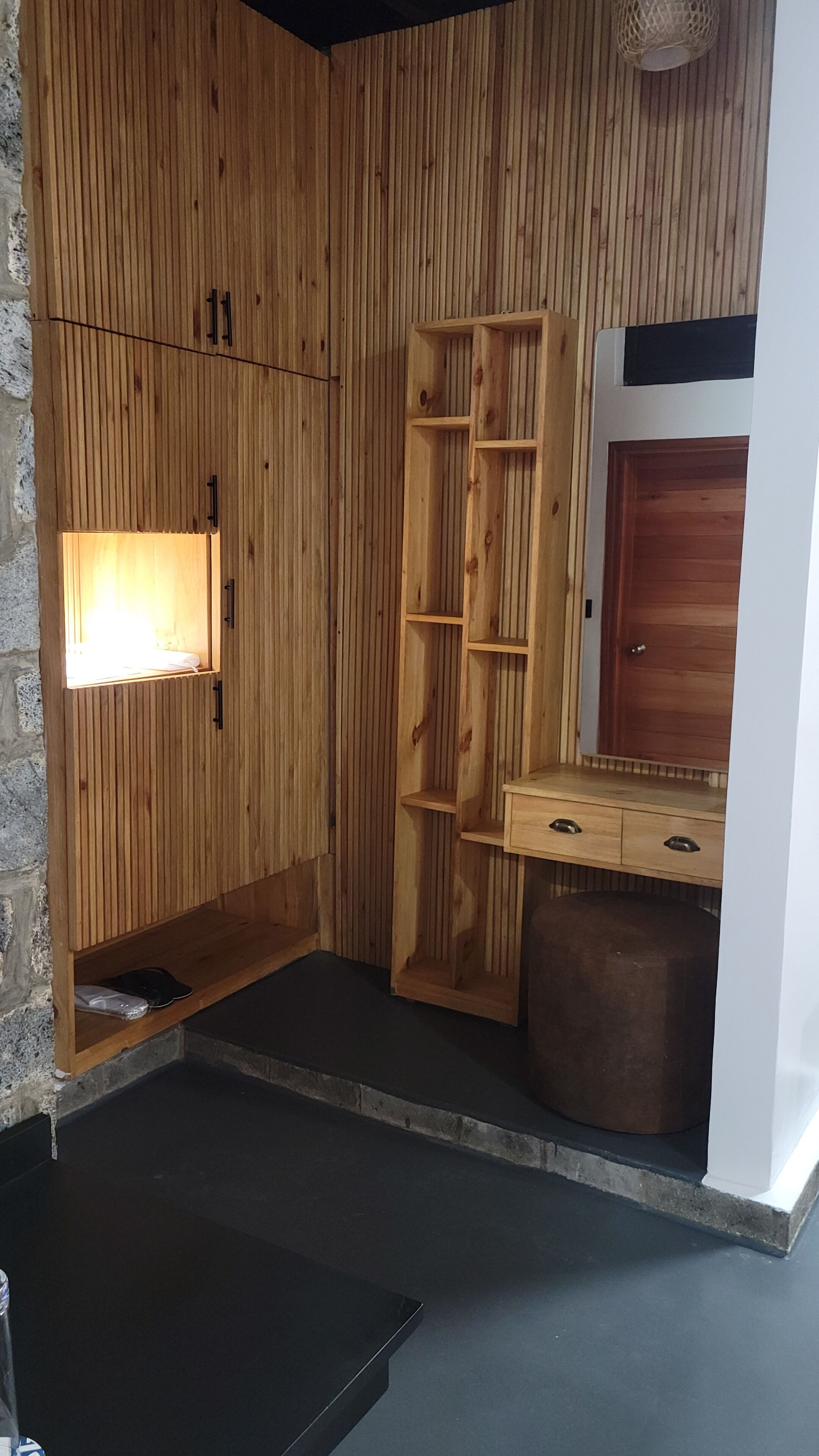 A wooden room with a built-in bench, a mirror, and a small table.