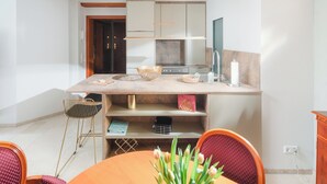 Une cuisine moderne dotée d’un îlot central, d’un coin repas avec une table ronde et d’un fauteuil rouge recouvert de tissu.