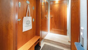 Un couloir en bois avec un banc, une porte et un sac orné d’un logo.