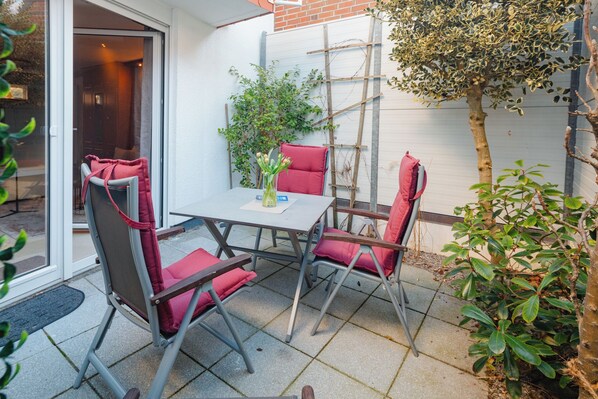 Une terrasse avec une table et quatre chaises, une échelle et un arbre.