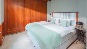 Une chambre à coucher avec un grand lit, une armoire en bois et une table de chevet avec une lampe.