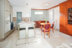 Una cocina moderna con una isla central, taburetes de bar, una mesa de comedor con sillas y armarios de madera.