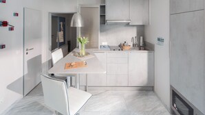 A modern kitchen with a white countertop, a built-in stove, and a hanging light fixture. - // VACATION APARTMENT BARKE 03 // (Norderney)