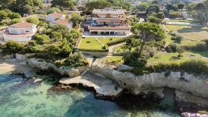 Una propietat costanera amb una casa gran, una platja privada i un penya-segada rocosa.