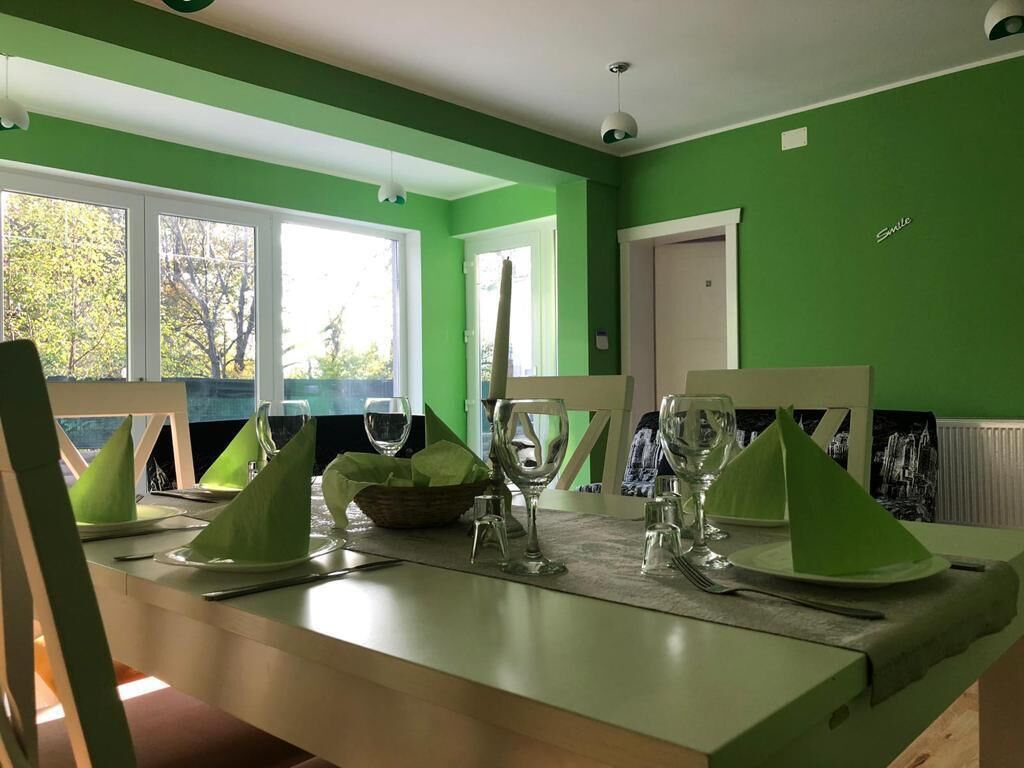 A dining area with a green wall, a window, and a door.