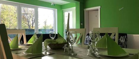 A dining area with a green wall, a window, and a door.