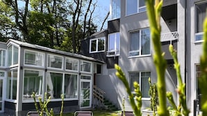 A modern building with a glass facade, outdoor seating area, and a staircase leading to an upper level. - Premont Guesthouse Bran (Bran)