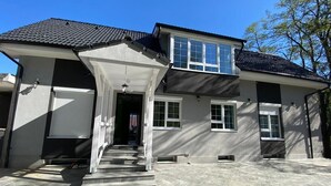 A two-story house with a garage, a covered front porch, and a driveway. - Premont Guesthouse Bran (Bran)
