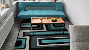 A modern room with a teal sofa, a wooden coffee table, and a black and teal rug. - Premont Guesthouse Bran (Bran)