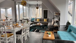A spacious living area with a dining table set for six, a sofa, and a coffee table. - Premont Guesthouse Bran (Bran)