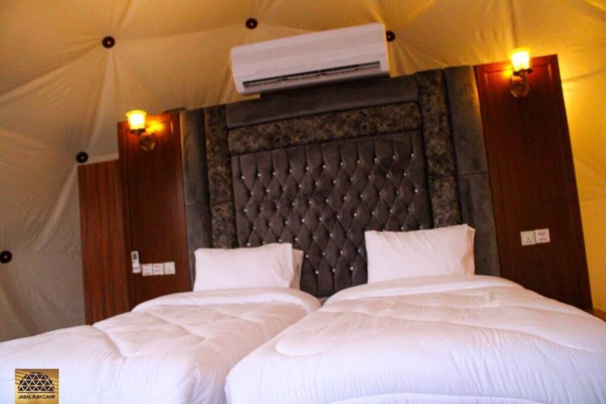 A double bed with a tufted headboard in a tent-style room.