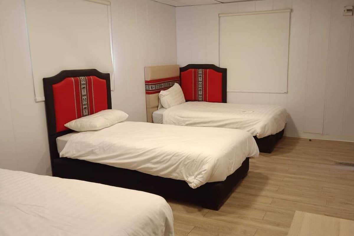 A hotel room with two beds, each with a red headboard and white bedding.