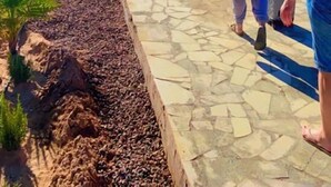Um grupo de pessoas caminhando por um caminho pavimentado em uma paisagem desértica, com montanhas ao fundo.