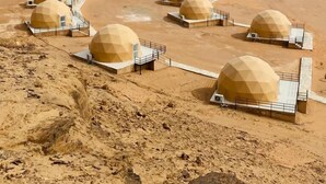 Paisagem desértica com diversas estruturas em forma de cúpula dispostas em padrão semicircular.