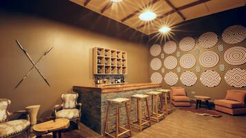 A bar area with stools, a wooden shelf with bottles, and a patterned wall.