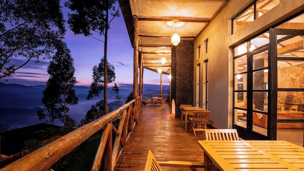 A wooden deck with outdoor seating, overlooking a mountainous landscape at dusk. - Kaara Gorilla Mountain Lodge (Bugambira)