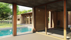 Ein moderner Innenpoolbereich mit Glaswänden, einer Lounge und Blick auf den Garten.