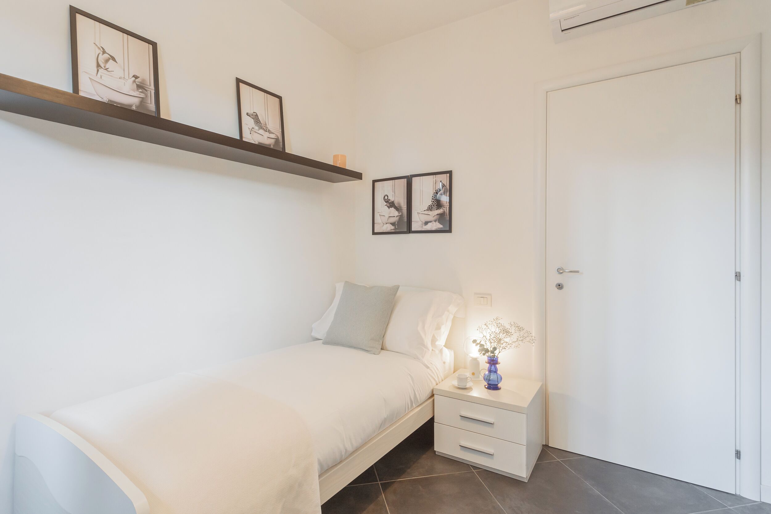 A neatly arranged bedroom with a bed, bedside table, and a door.