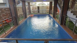 Una piscina con superficie azul, rodeada de barandillas de metal y un muro de ladrillo.
