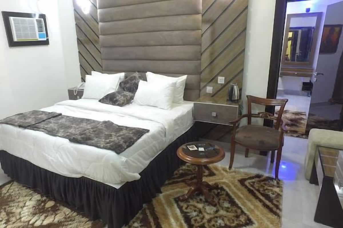 A bedroom with a bed, bedside table, chair, and a small round table.
