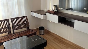 Un espacio habitable compacto con kitchenette, un comedor con mesa y sillas, un televisor montado en la pared y una ventana con cortinas.
