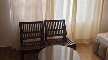 Una habitación con un banco de madera, una mesa redonda y una cama.