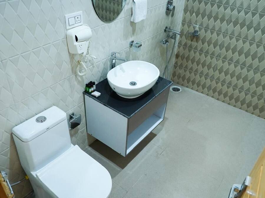 Un baño con inodoro blanco, un lavamanos con espejo y una zona de ducha.