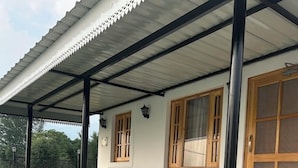 Un espacio de estar al aire libre cubierto con dos sillas, una escalera de madera y una casa con entrada de azulejos.