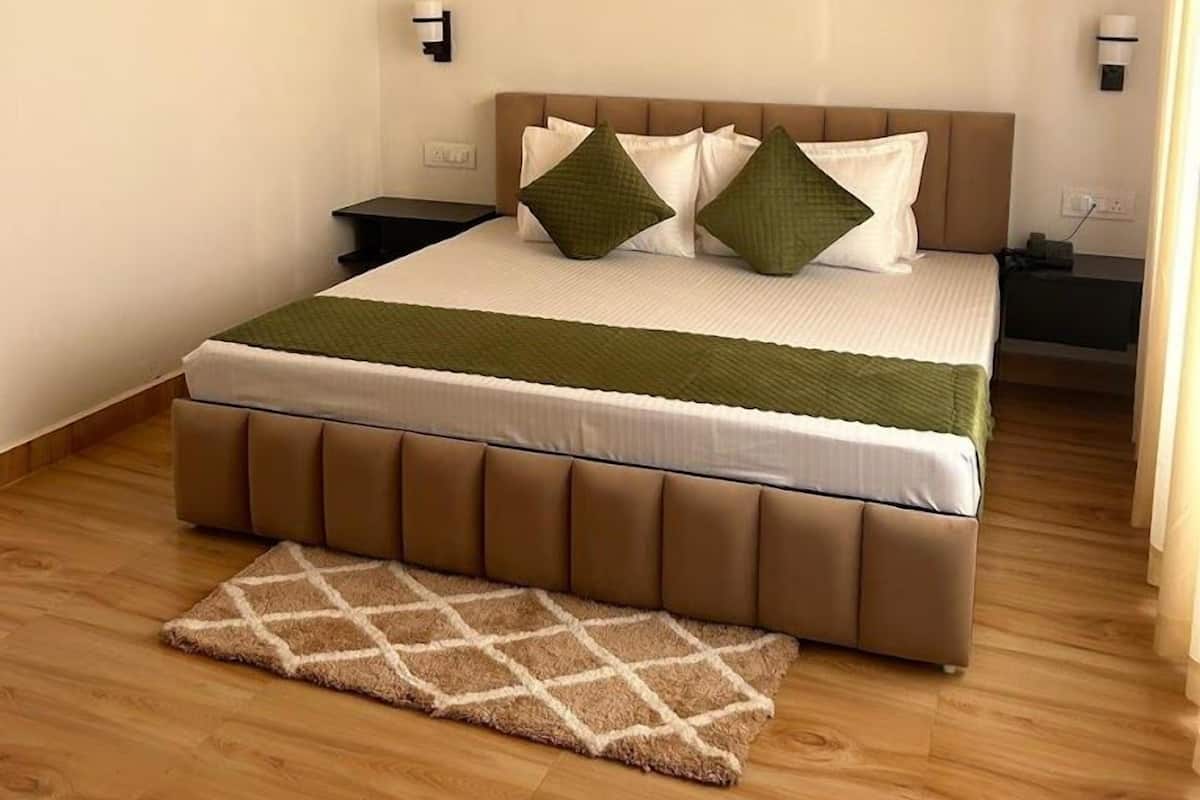 A bedroom with a wooden ceiling, a bed with a brown headboard, two bedside tables, and a green throw blanket.