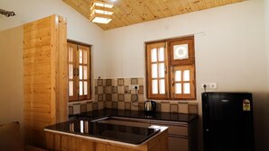 Una cocina con armarios de madera, encimera negra, hervidor y refrigerador.