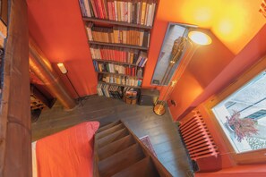 A staircase leading to a room with a bookshelf, a radiator, and a window with a view. - La Corte Degli Artisti by Rent all Como (Blevio)