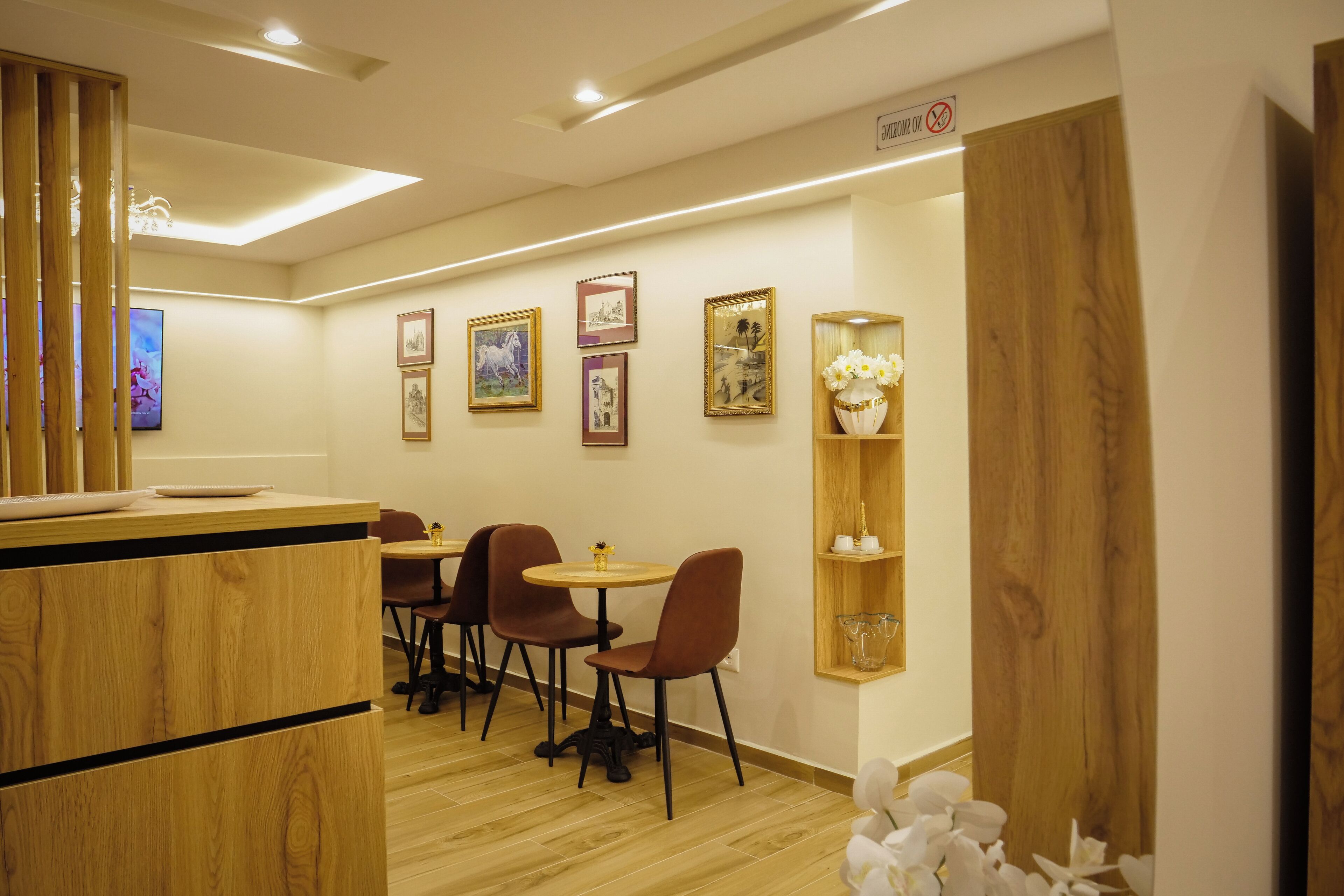 A restaurant interior with wooden furniture, framed artwork on the walls, and a small table with chairs.
