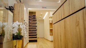 Un intérieur moderne avec un escalier en bois, un comptoir d’accueil et un panneau indiquant qu’il est interdit de fumer.
